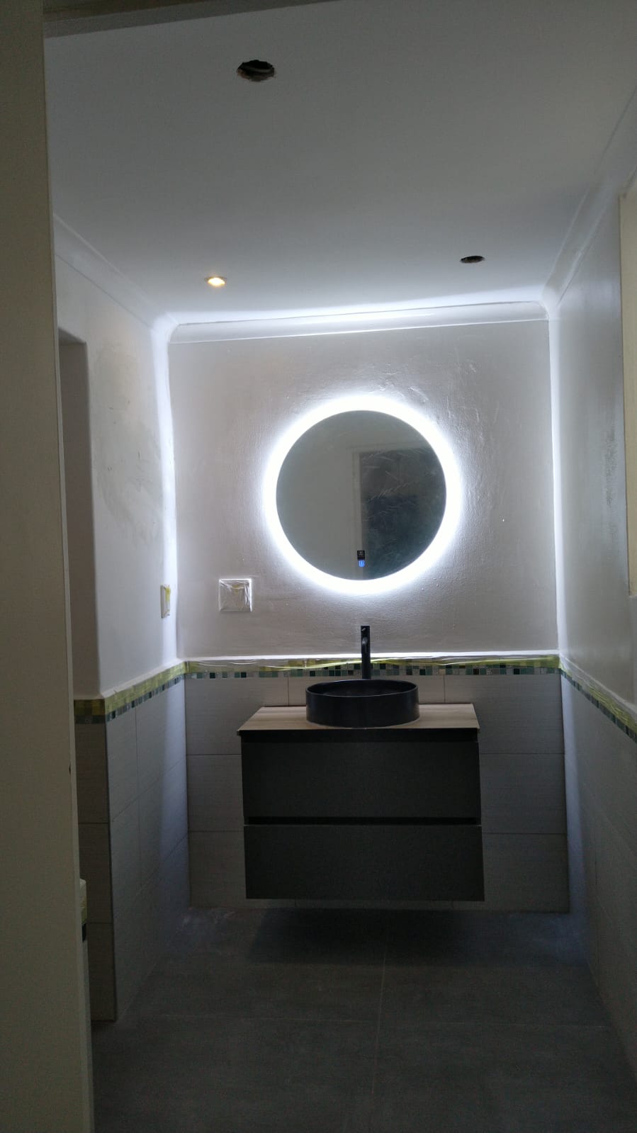 Modern bathroom with black floating vanity and LED illuminated circular mirror