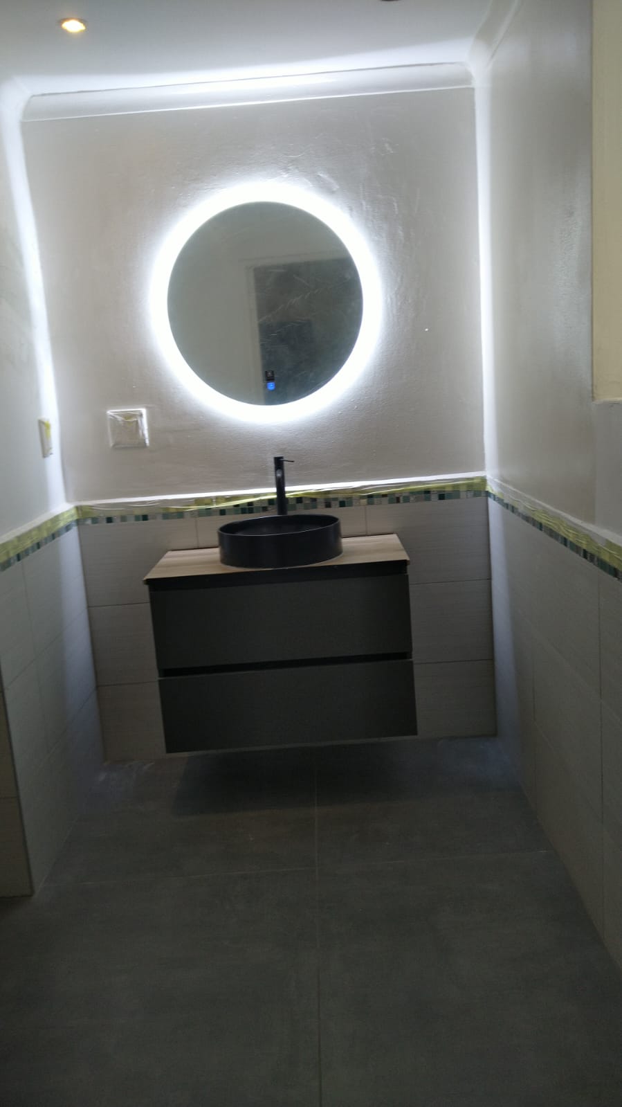 Modern bathroom vanity with black vessel sink and LED mirror on white subway tile