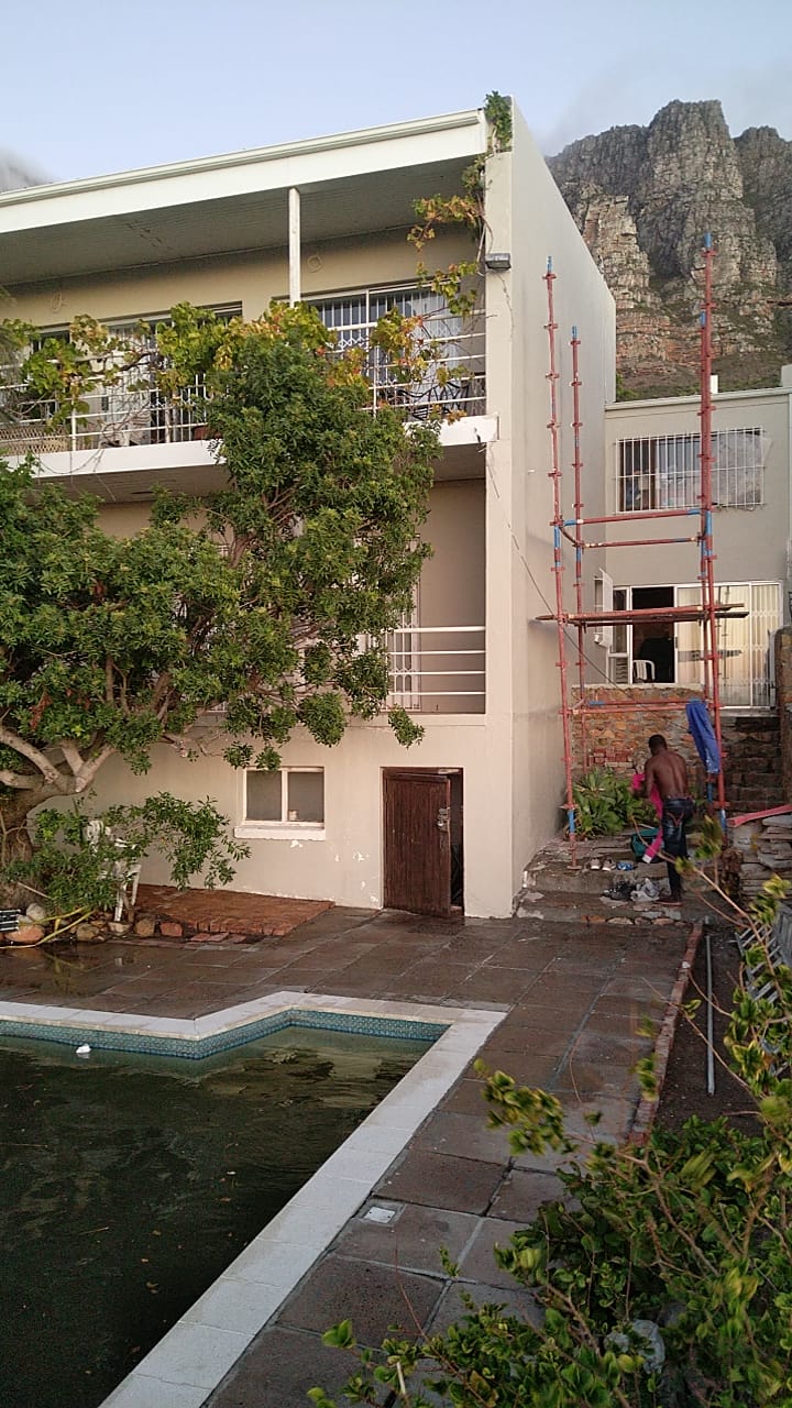 Modern multi-level residential building with pool and mountain backdrop under construction