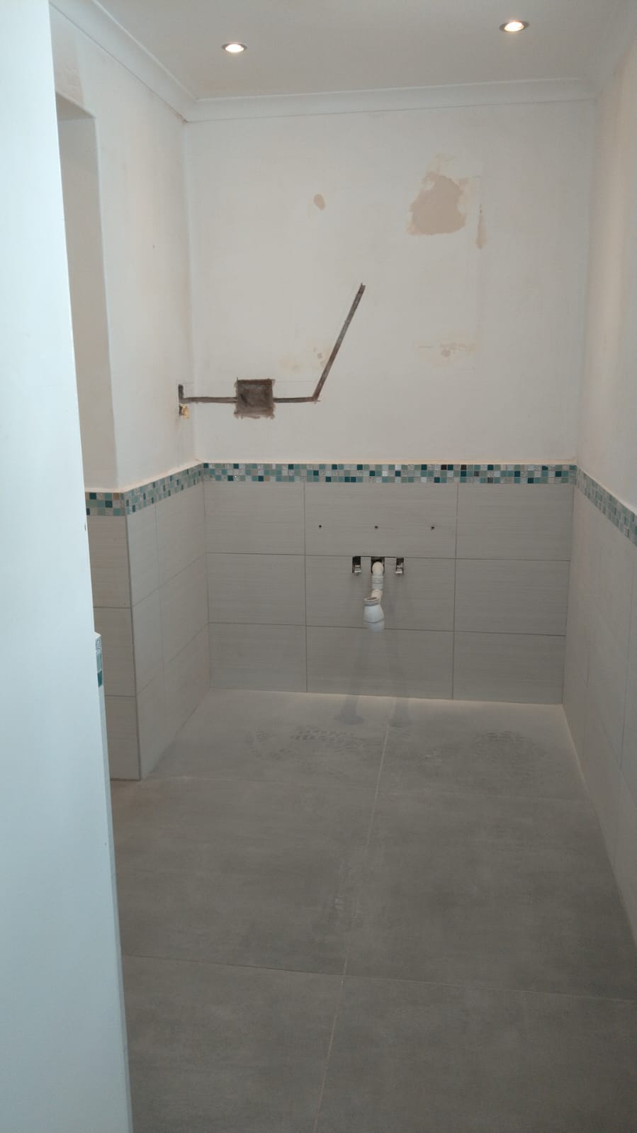 Newly renovated bathroom with white tile walls and decorative blue tile border