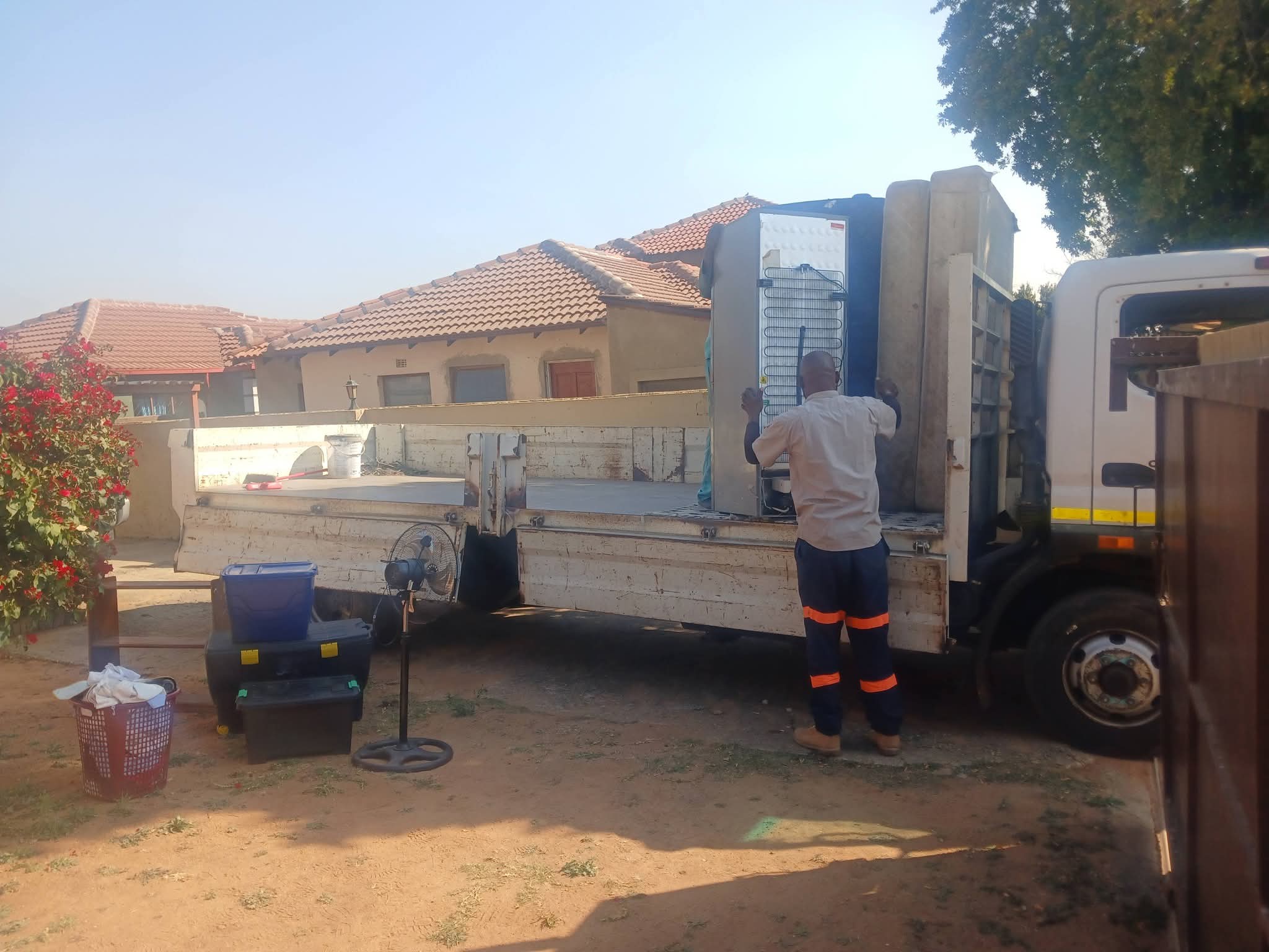 Movers loading furniture and belongings into a truck outside a residential house