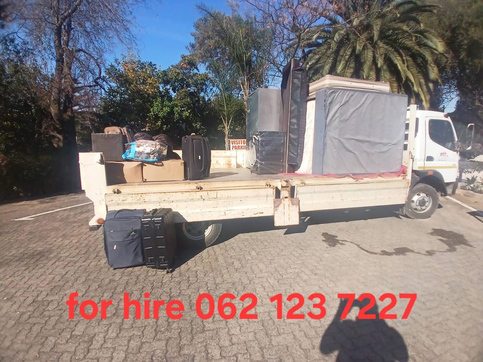 Moving trucks and equipment parked at a lot with the contact number 062 123 7227 displayed