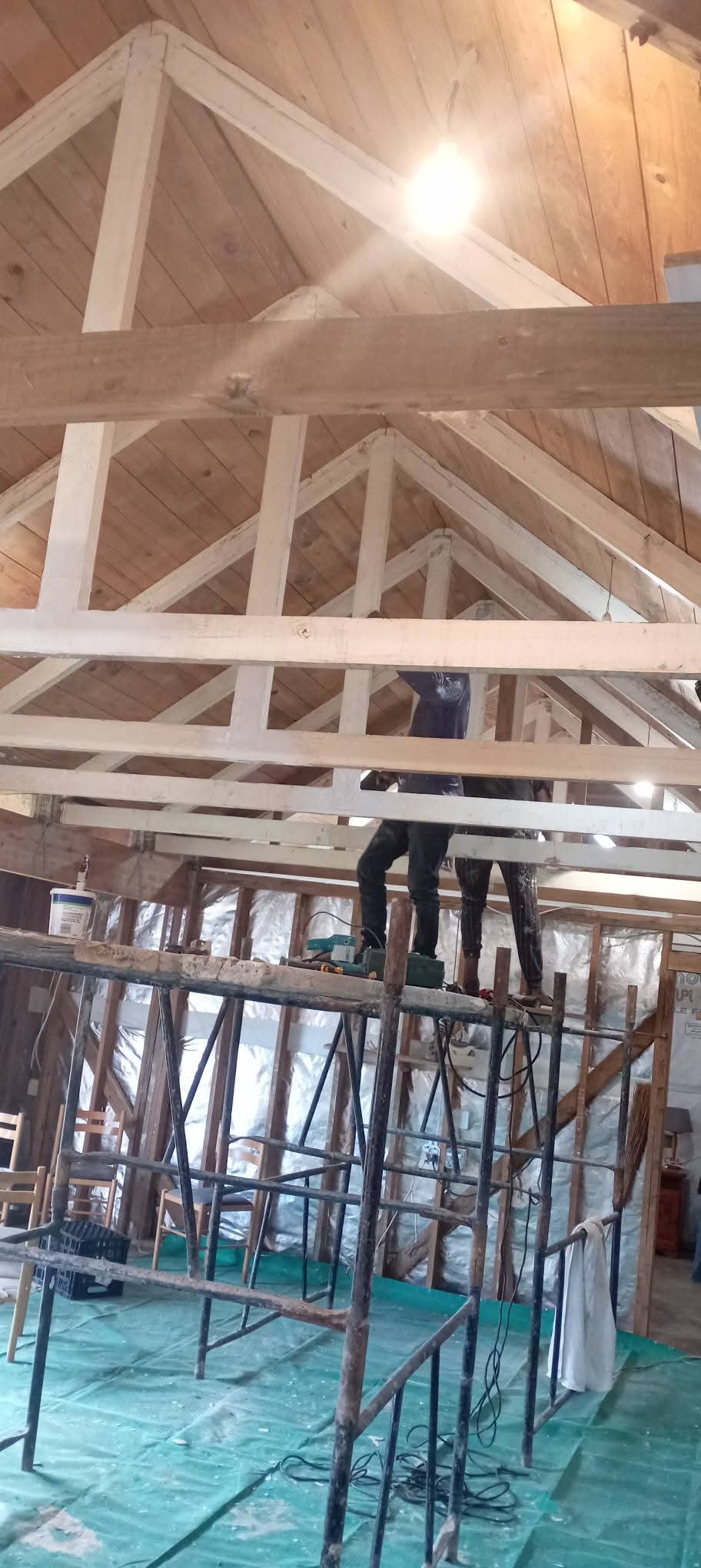 Interior construction with exposed wooden roof trusses and scaffolding