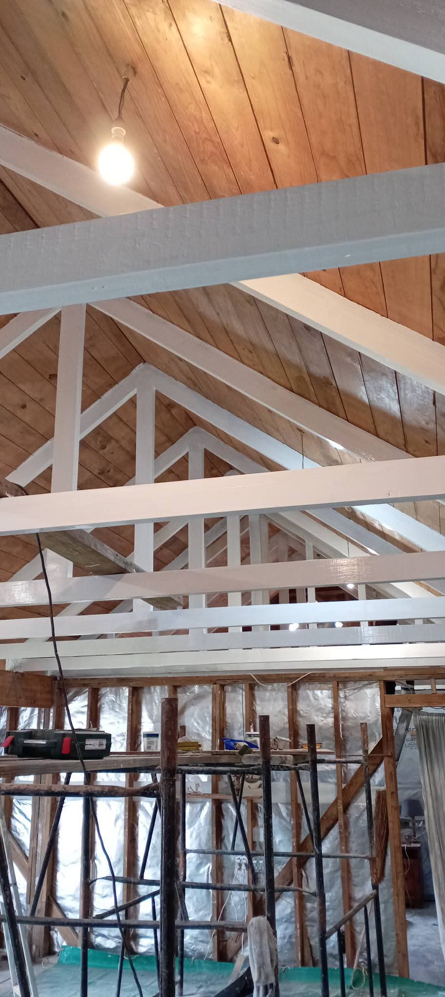 Interior of house under construction with exposed wooden roof beams and pendant light