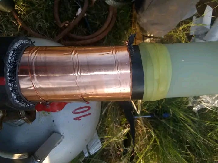 Copper downspout with green adapter fitting installed on site