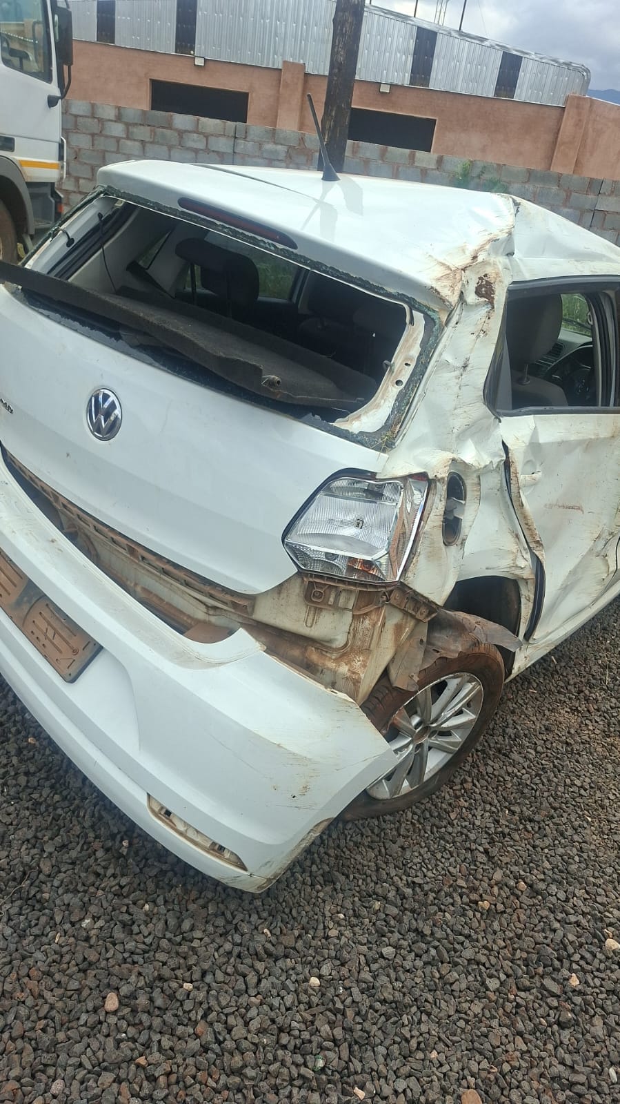 Severely damaged white Volkswagen vehicle with extensive collision damage to front end and roof