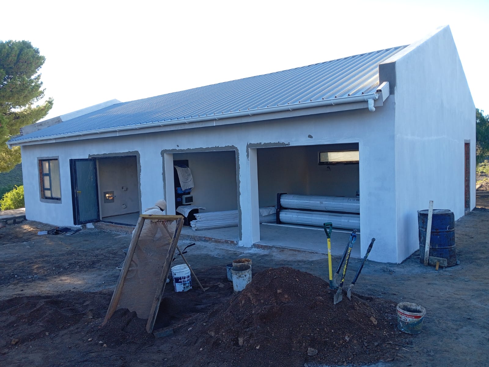 White house under construction with blue metal roof