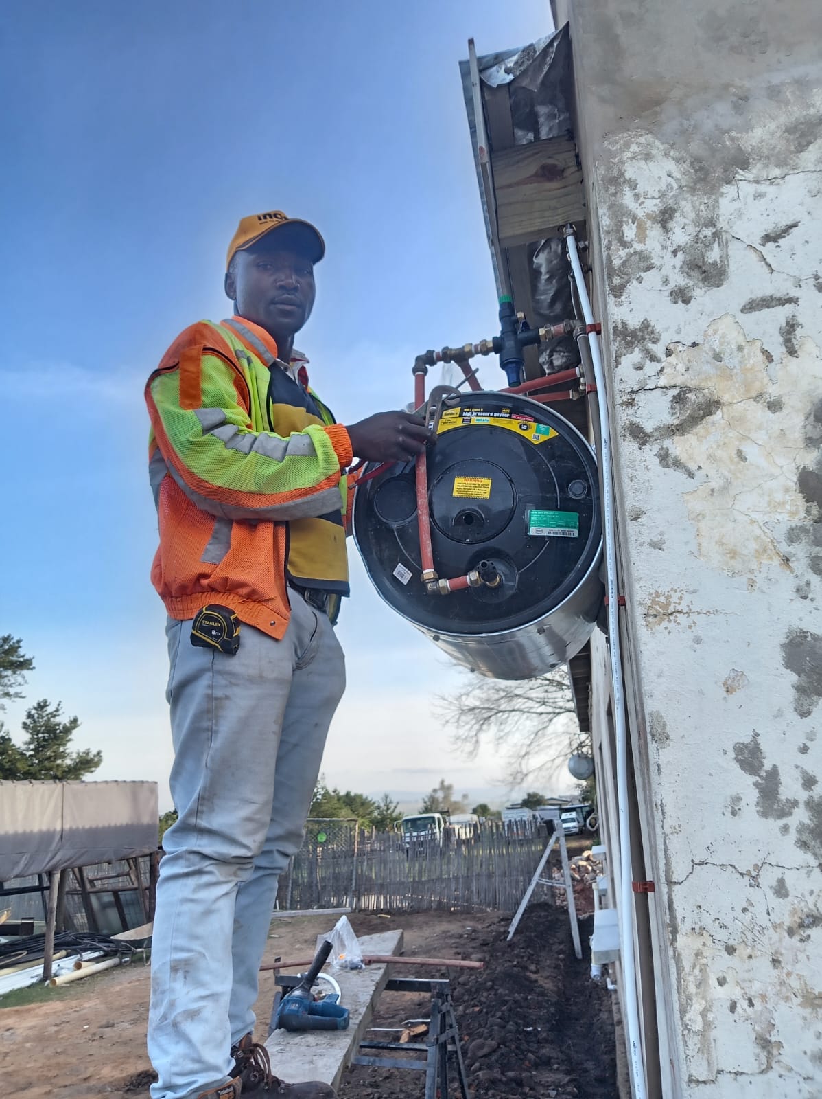 Worker installing pipe fitting on concrete wall