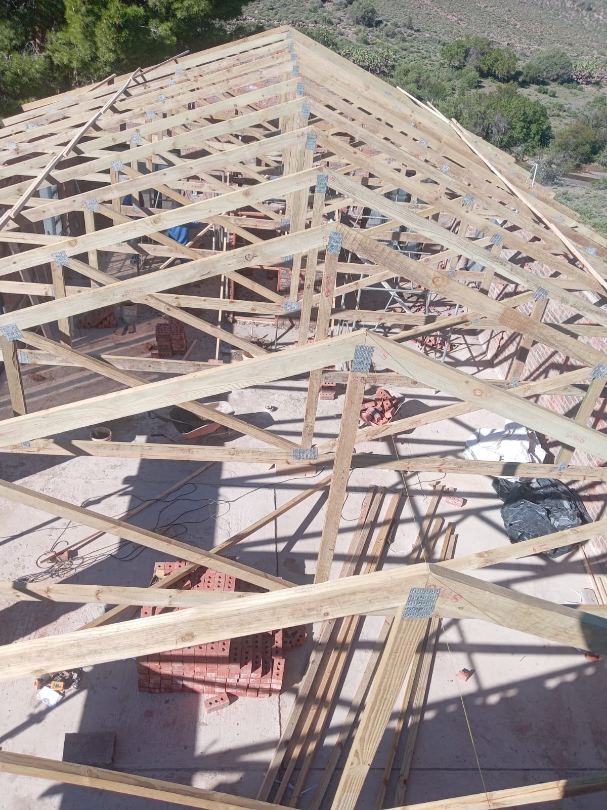 Residential roof under construction showing exposed wooden trusses and rafters