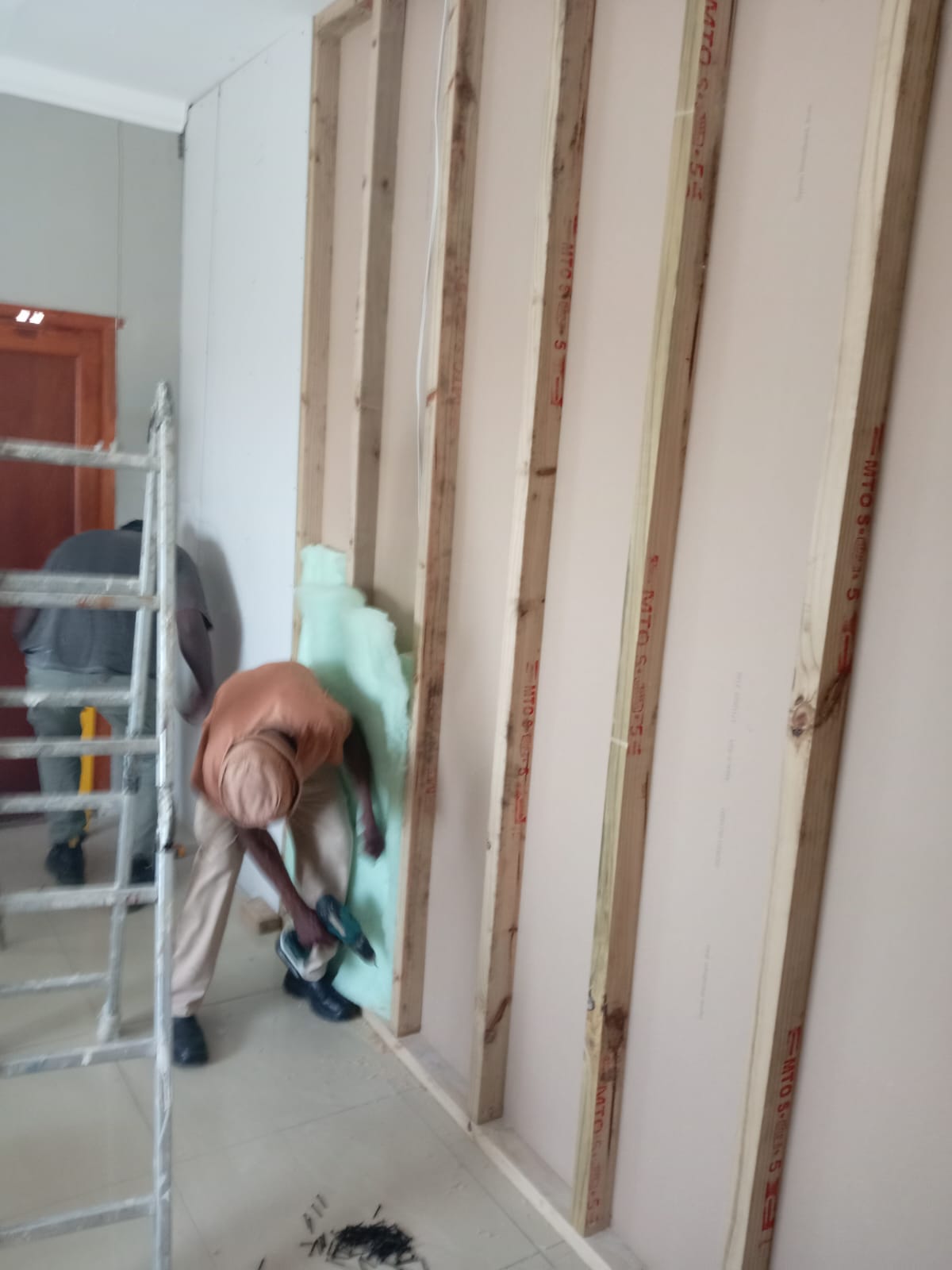 Worker painting an interior wall green