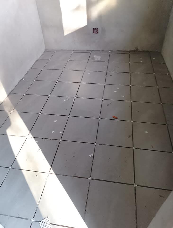 Bathroom with gray ceramic floor tiles being laid