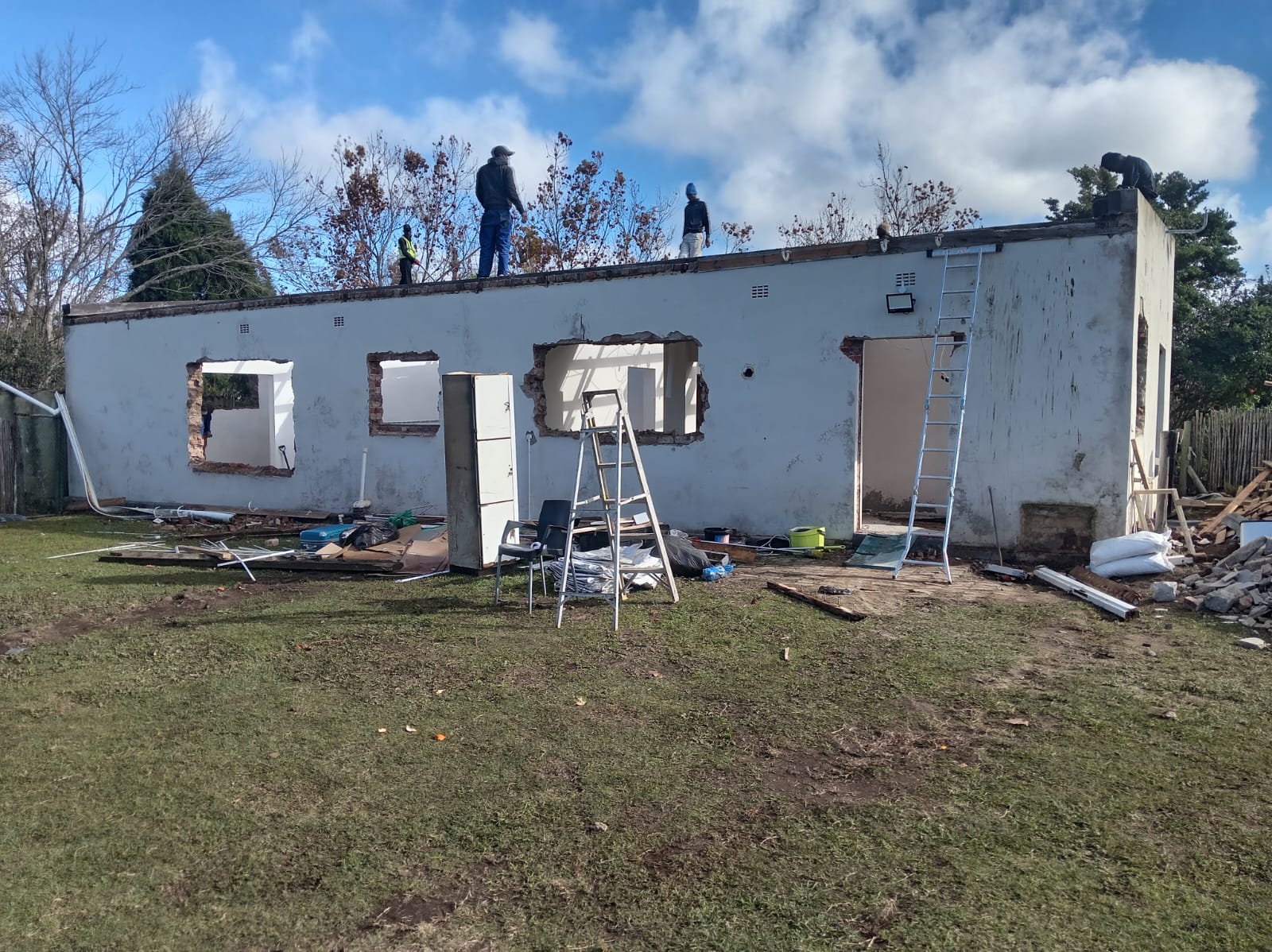 White residential building under renovation with workers on roof