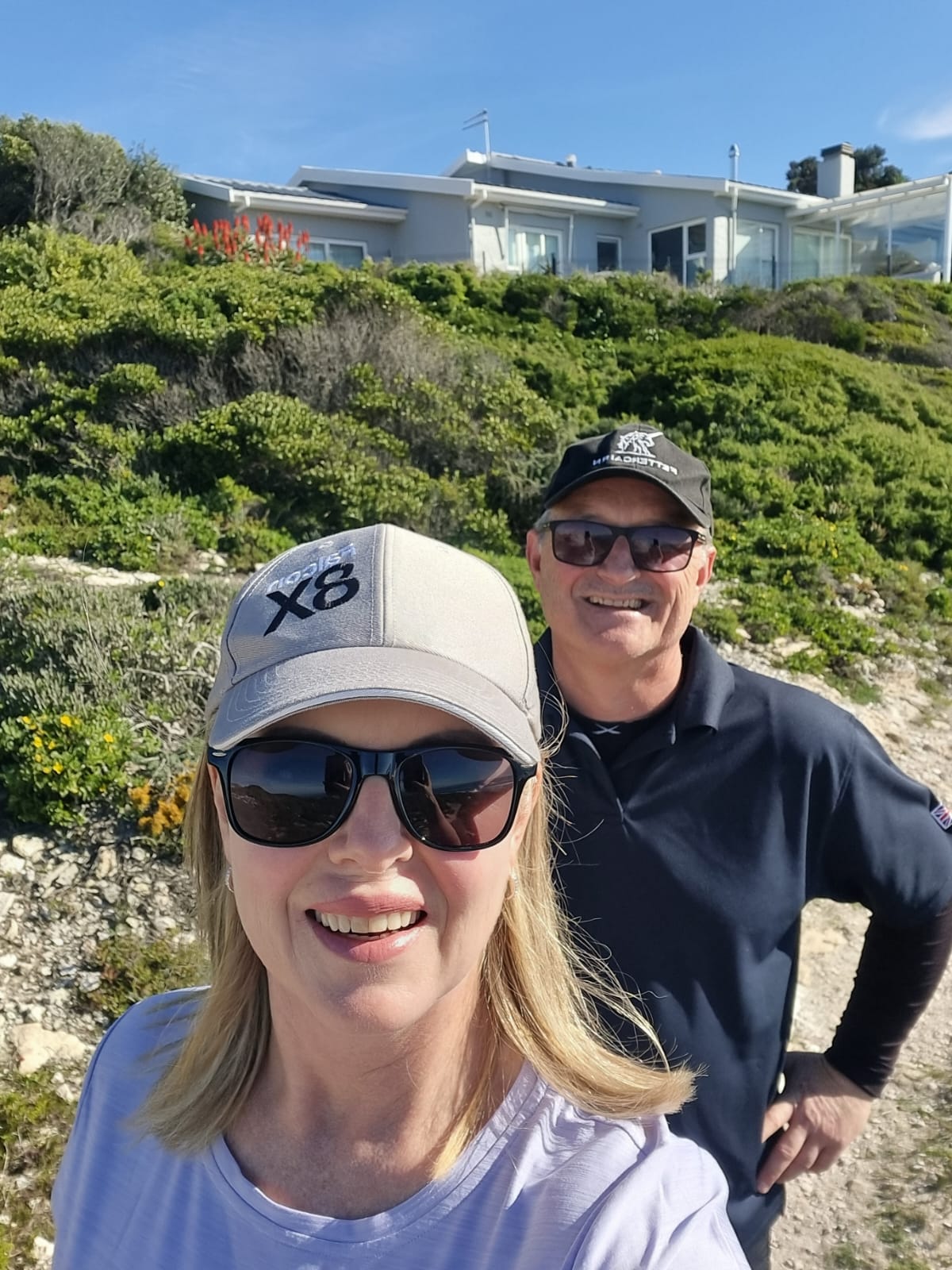 Couple posing on a hillside with lush green vegetation in Yzerfontein