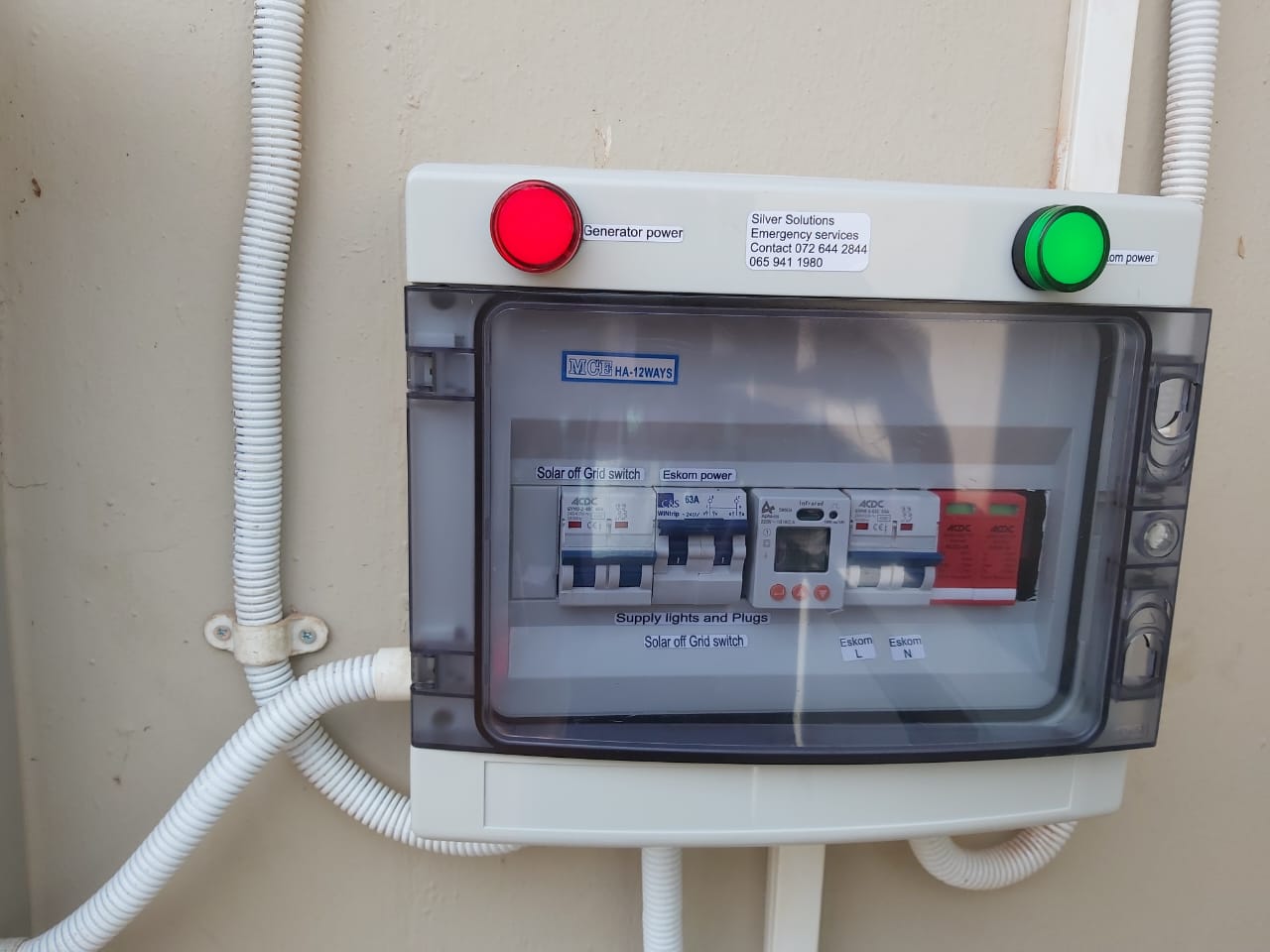 Electrical distribution panel with red and green indicator lights showing solar and Eskom power switching