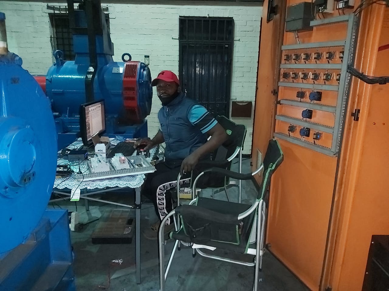 Technician in red cap monitoring industrial machinery at workstation