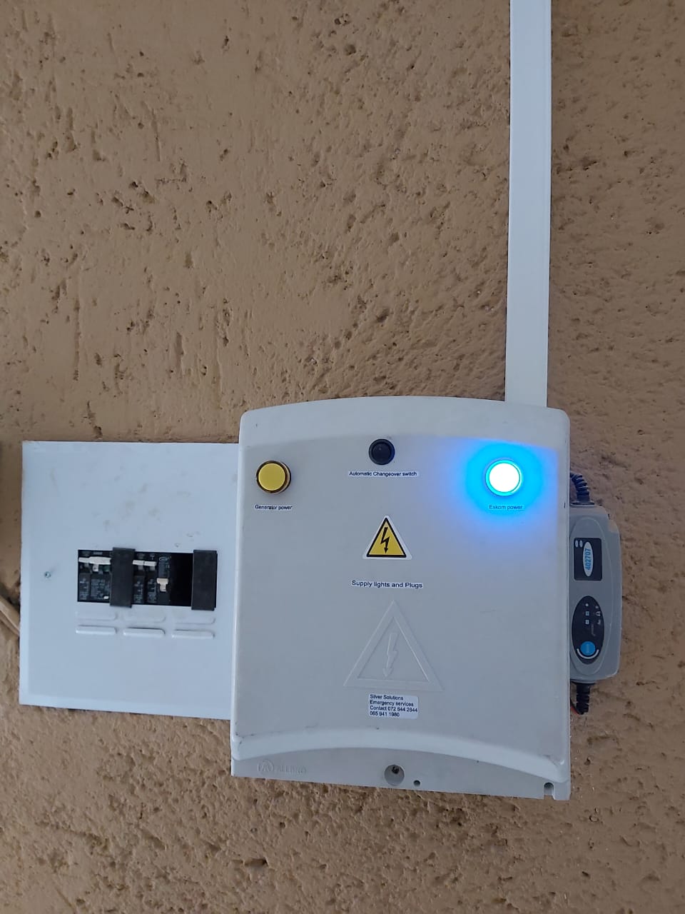 White electrical control panel with glowing blue power indicator light