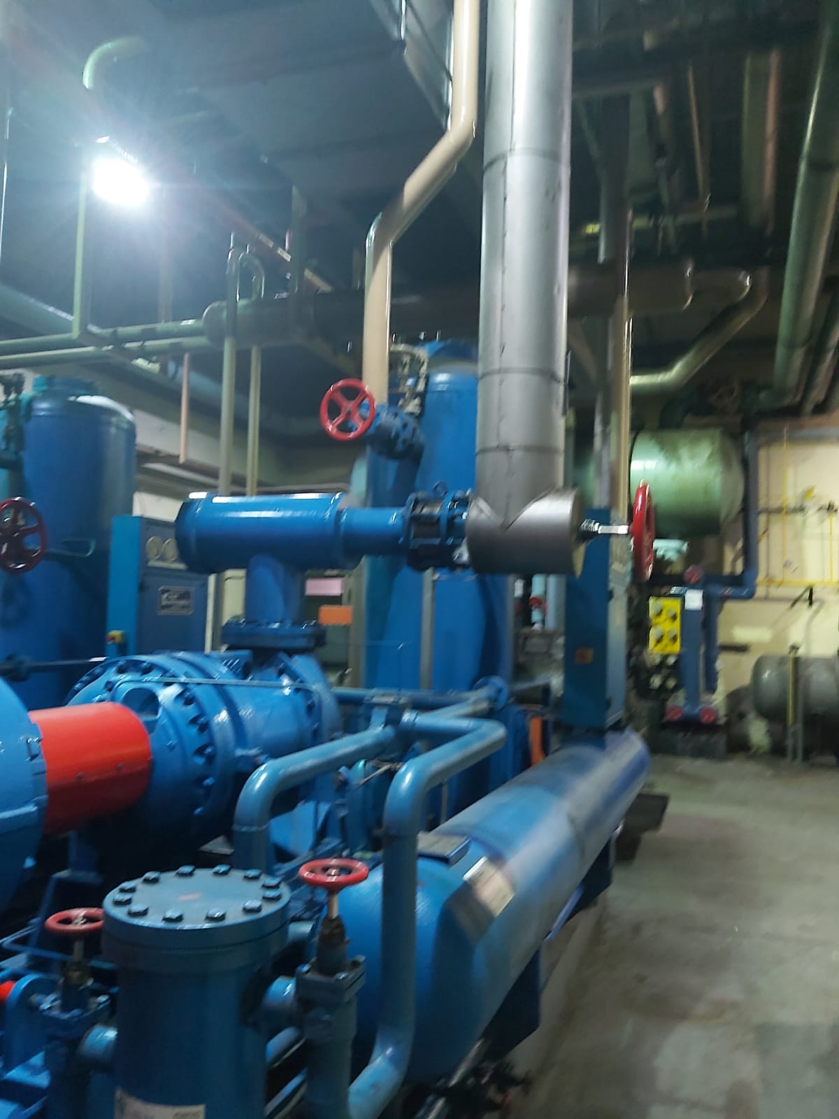 Industrial pump and piping system with blue machinery and red valve handles