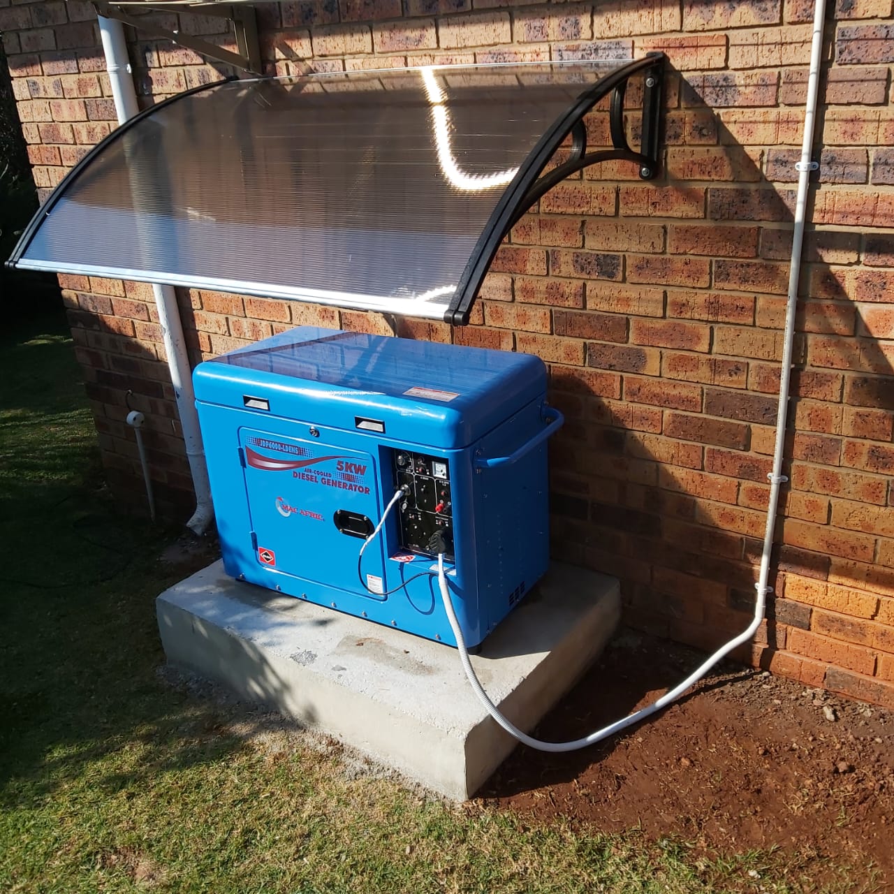 Blue 5KW diesel generator against brick wall with protective awning
