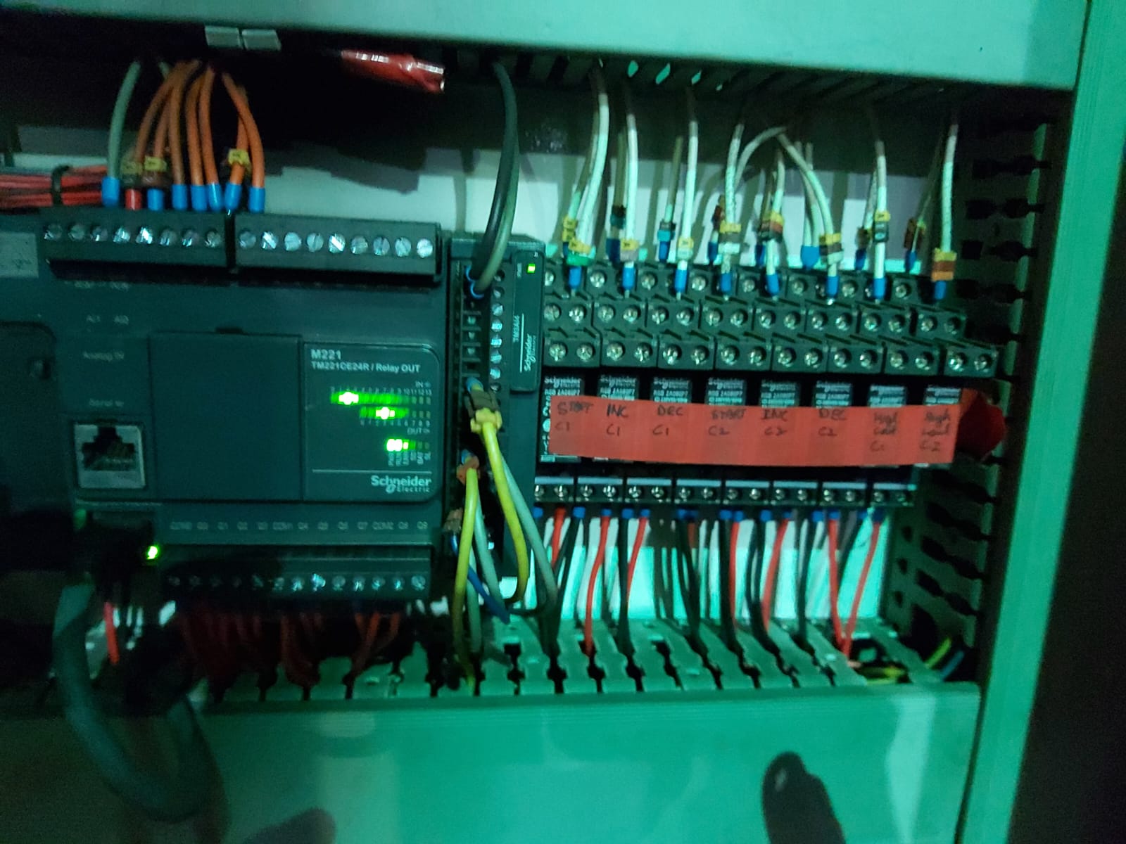 Industrial control panel with Schneider PLC and relay modules in green enclosure