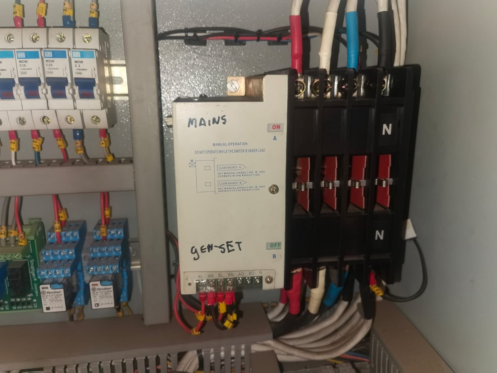 Electrical panel with manual changeover switch labeled MAINS and GEN-SET for generator backup power control