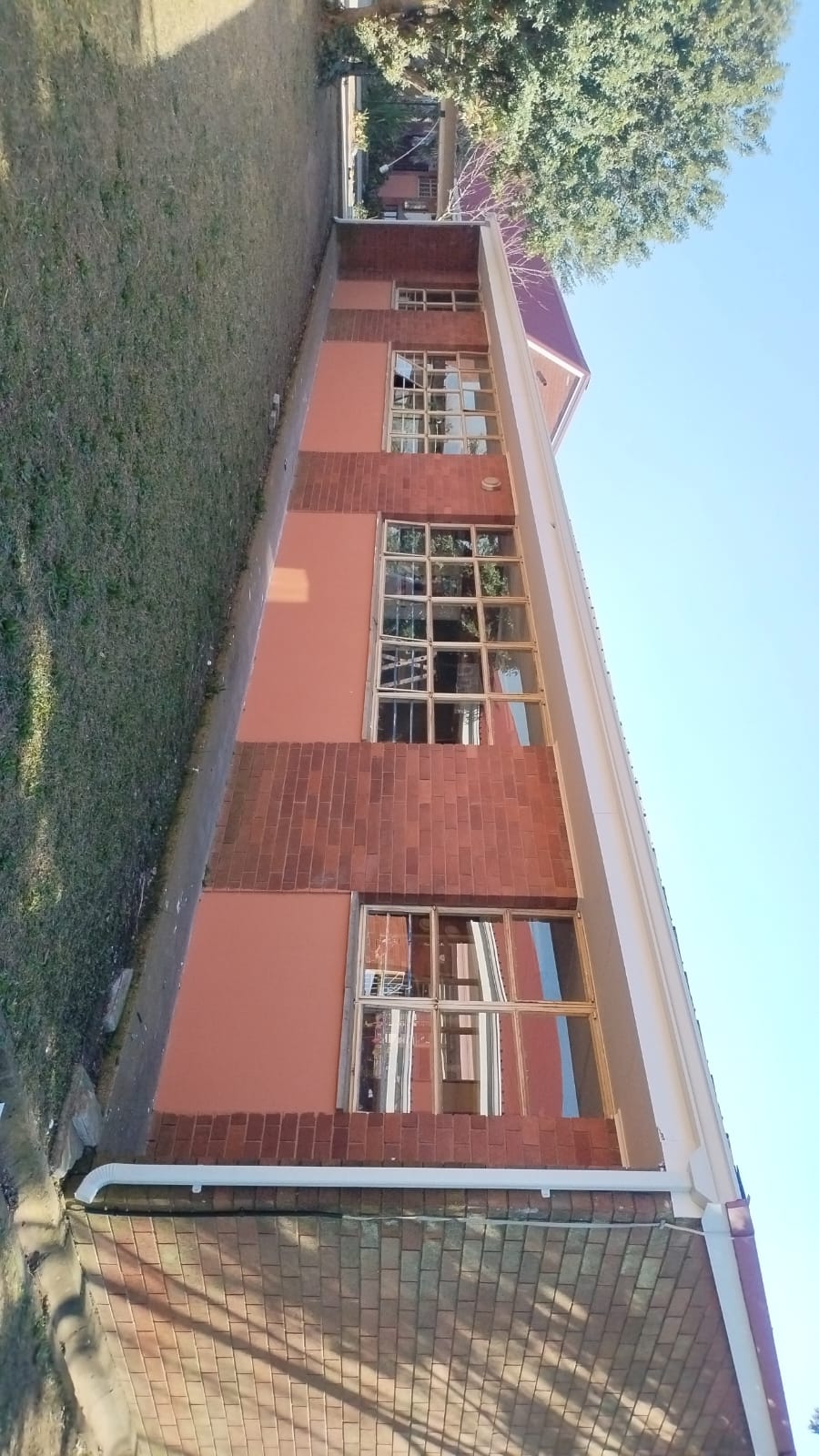 Narrow red brick residential building with purple roof and ivy
