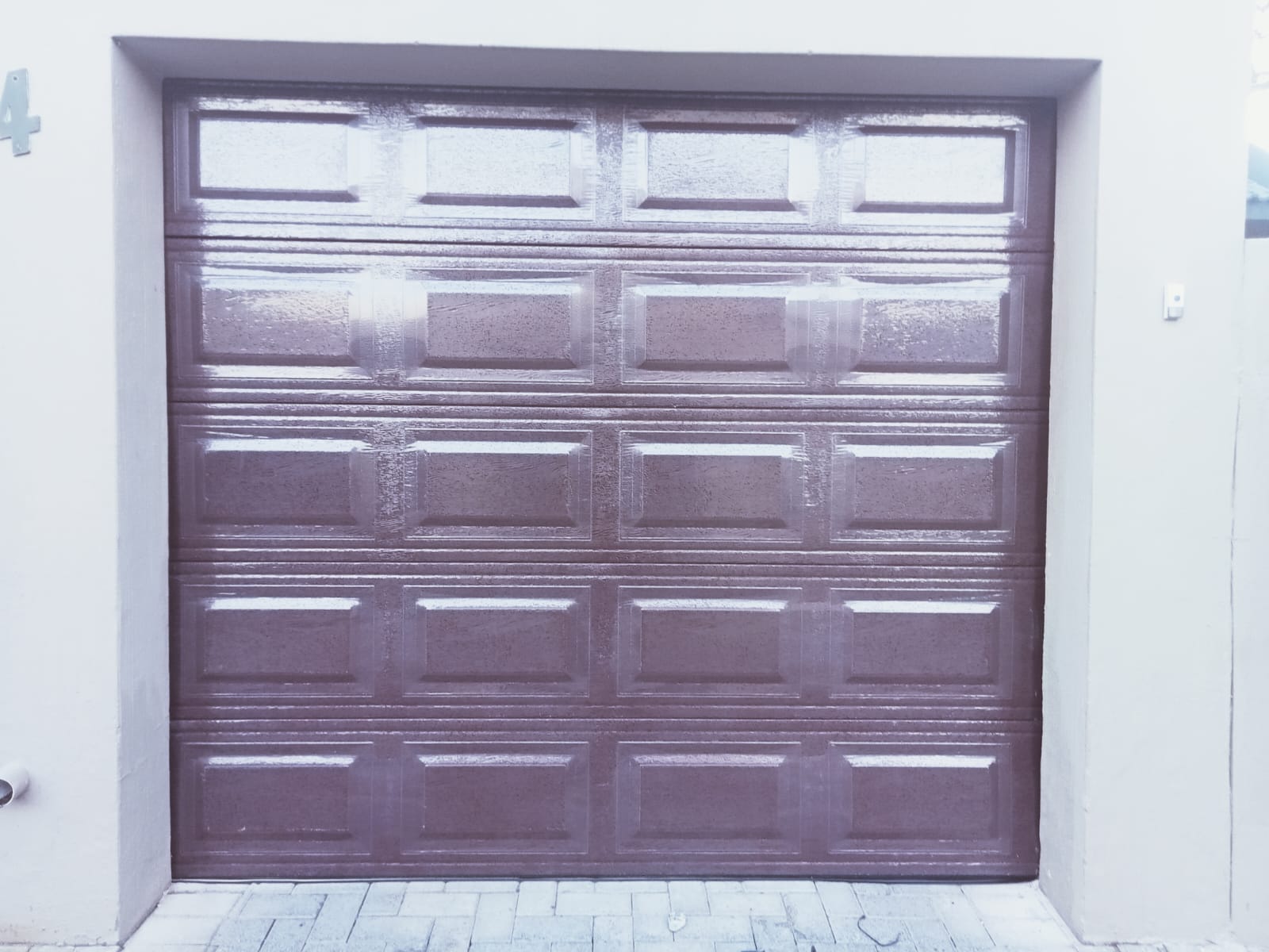 Purple garage door with frosted glass panels in the top section set into a white-framed opening