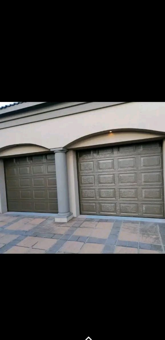 Residential garage with two green paneled doors featuring arched architectural details