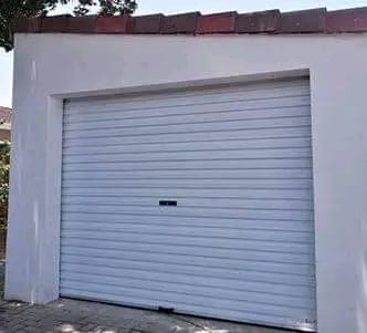 White garage with light blue horizontal roller door and brick roof