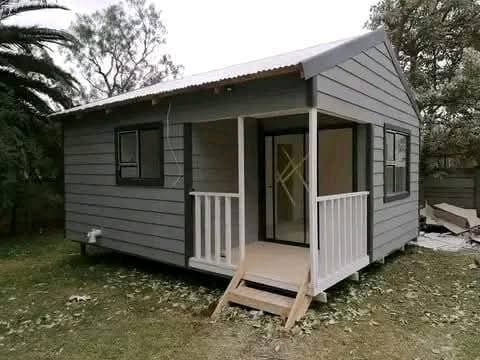 Small greyish-blue modern tiny house with white trim and front porch entrance