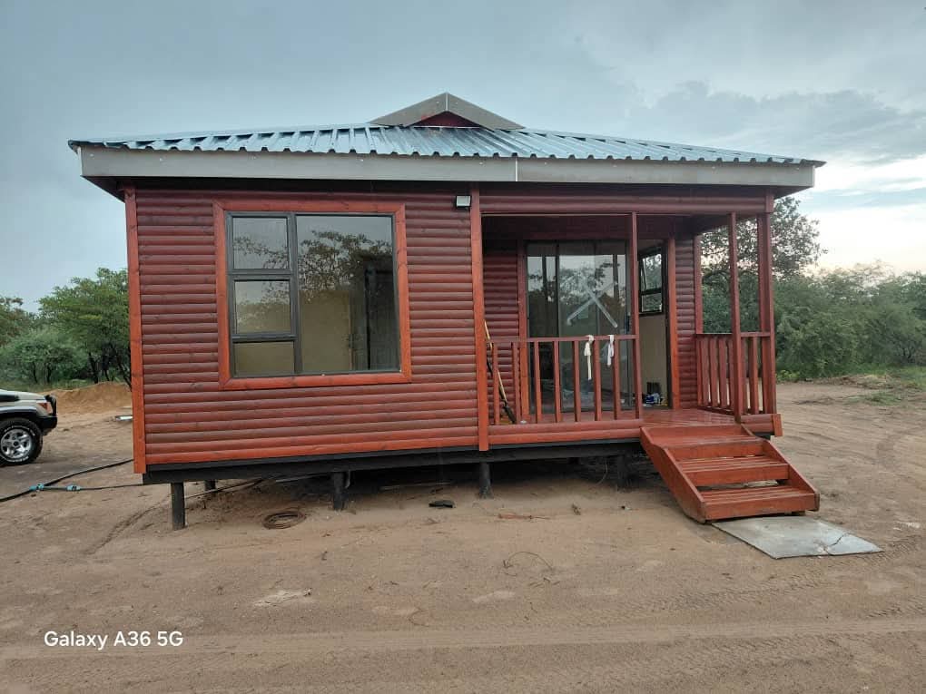 Compact red metal-sided mobile home with wooden deck