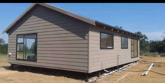 Modern single-story tiny house with tan horizontal siding and dark roof