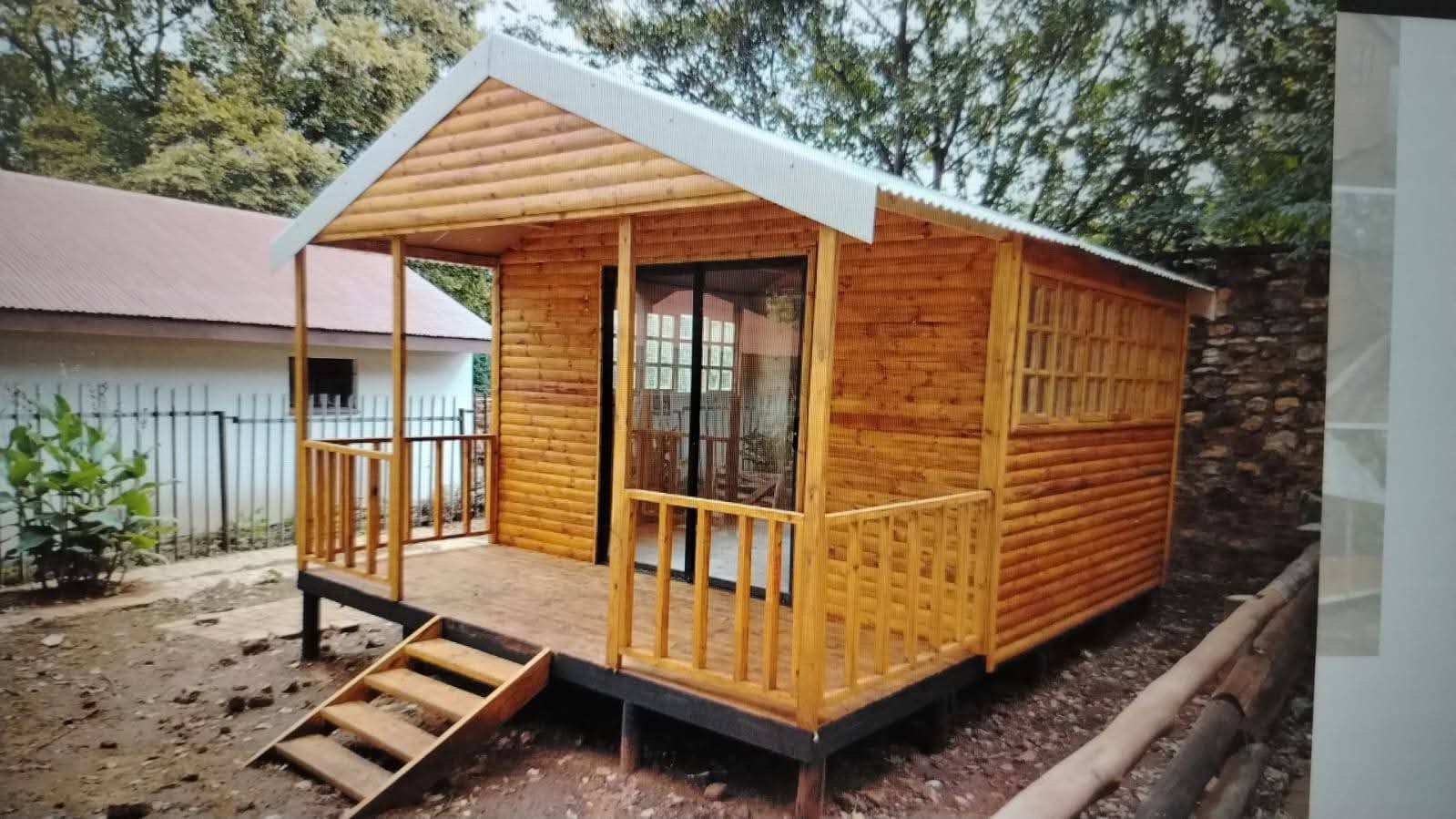 Wooden cabin with white metal roof and wraparound deck elevated on foundation
