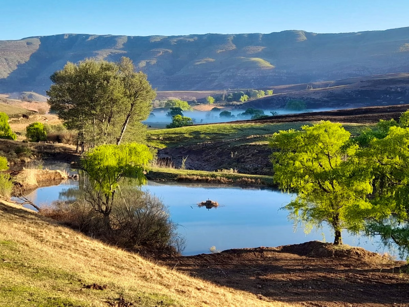 Calm river winding through agricultural fields with cliffs