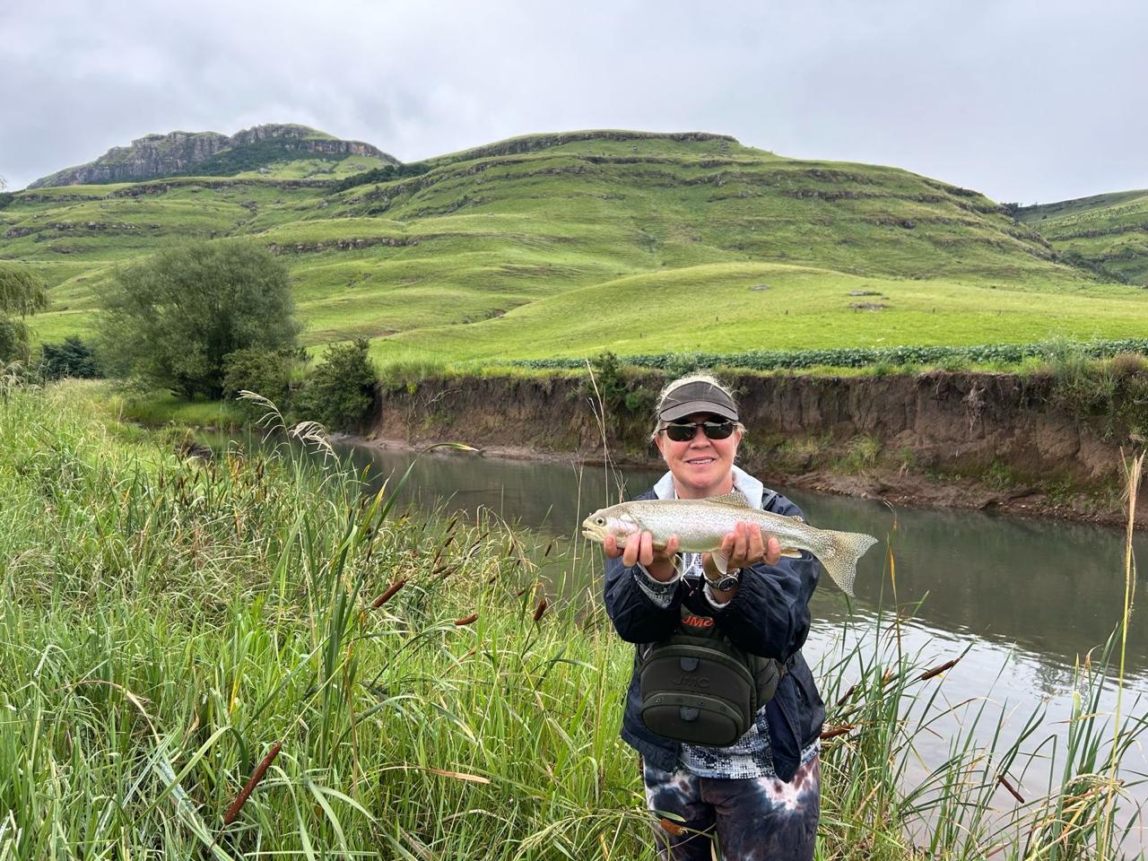 Fisherman proudly displaying a freshly caught trout in the river