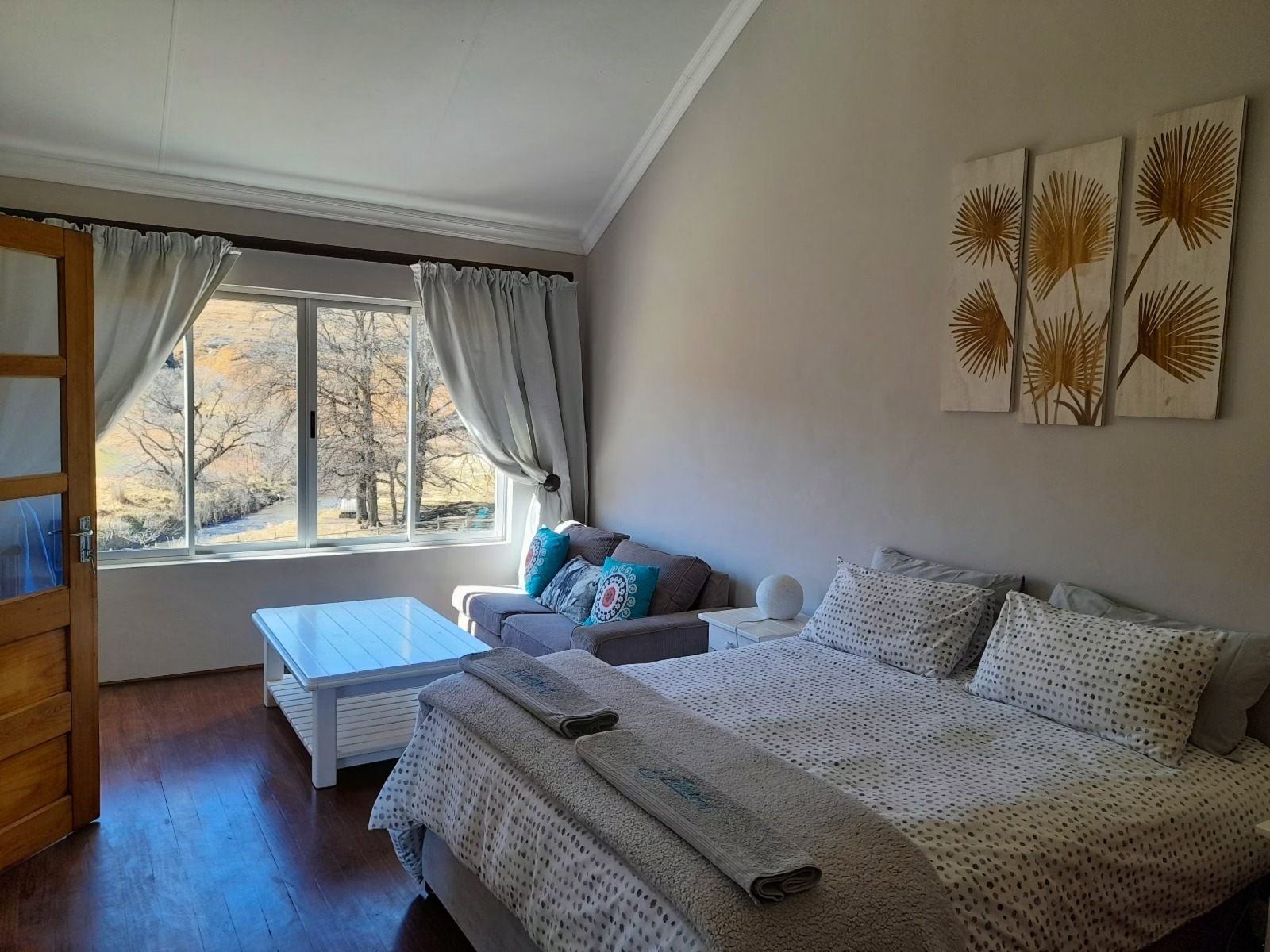 Bright double bedroom with gold botanical art and seating area