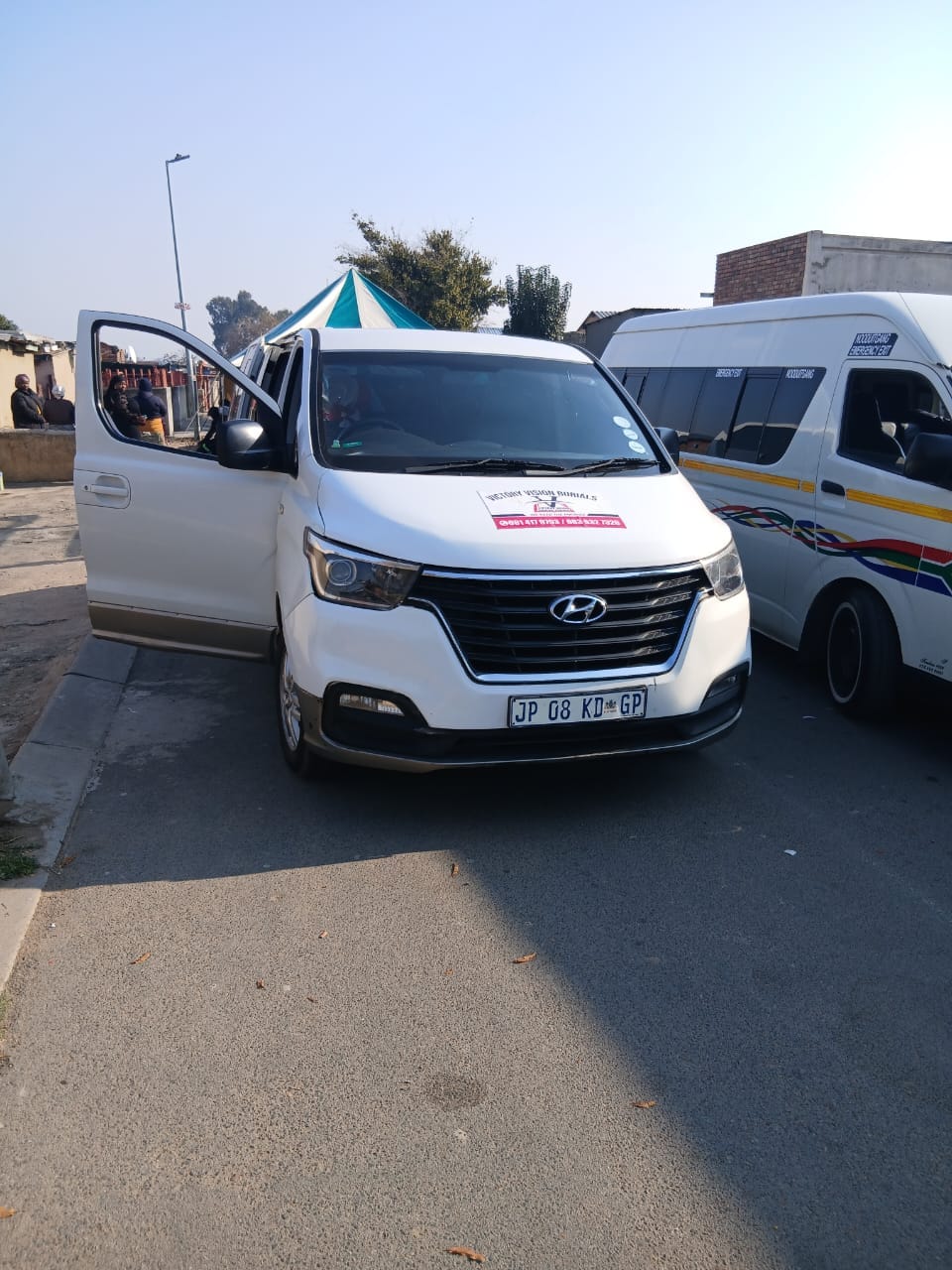 White van with open door and blue-striped tent
