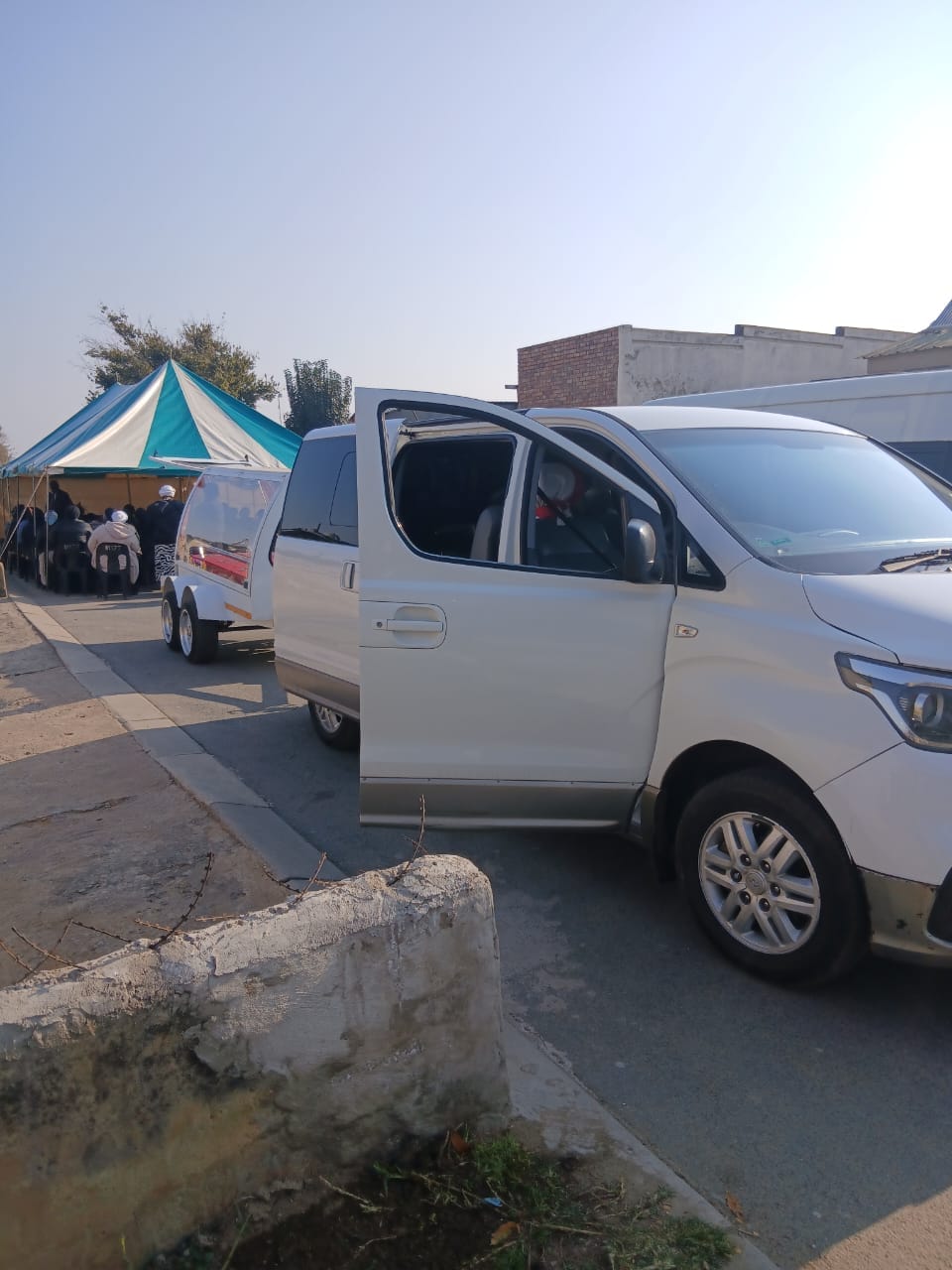 Vans and a tent with people gathered on a street
