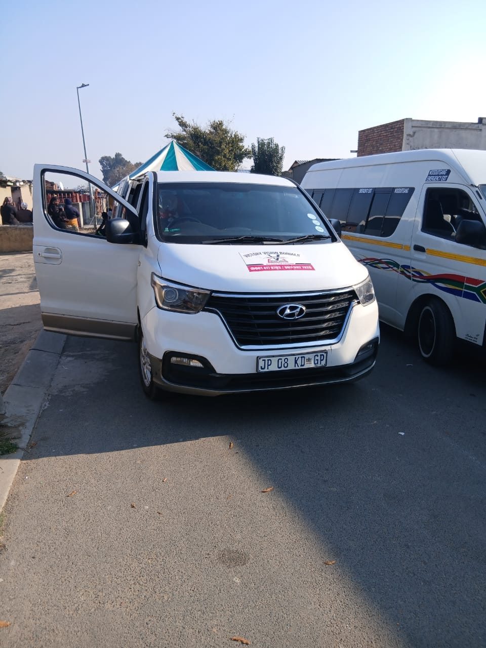 White van with open door and umbrella at a taxi stand
